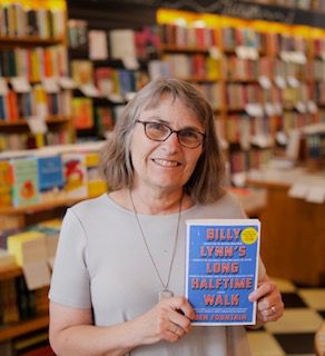 A picture of Jeanne Joesten smiling while holding a book in a bookstore